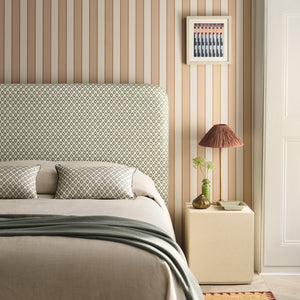 Neatly made bed with patterned headboard in a bedroom setting.