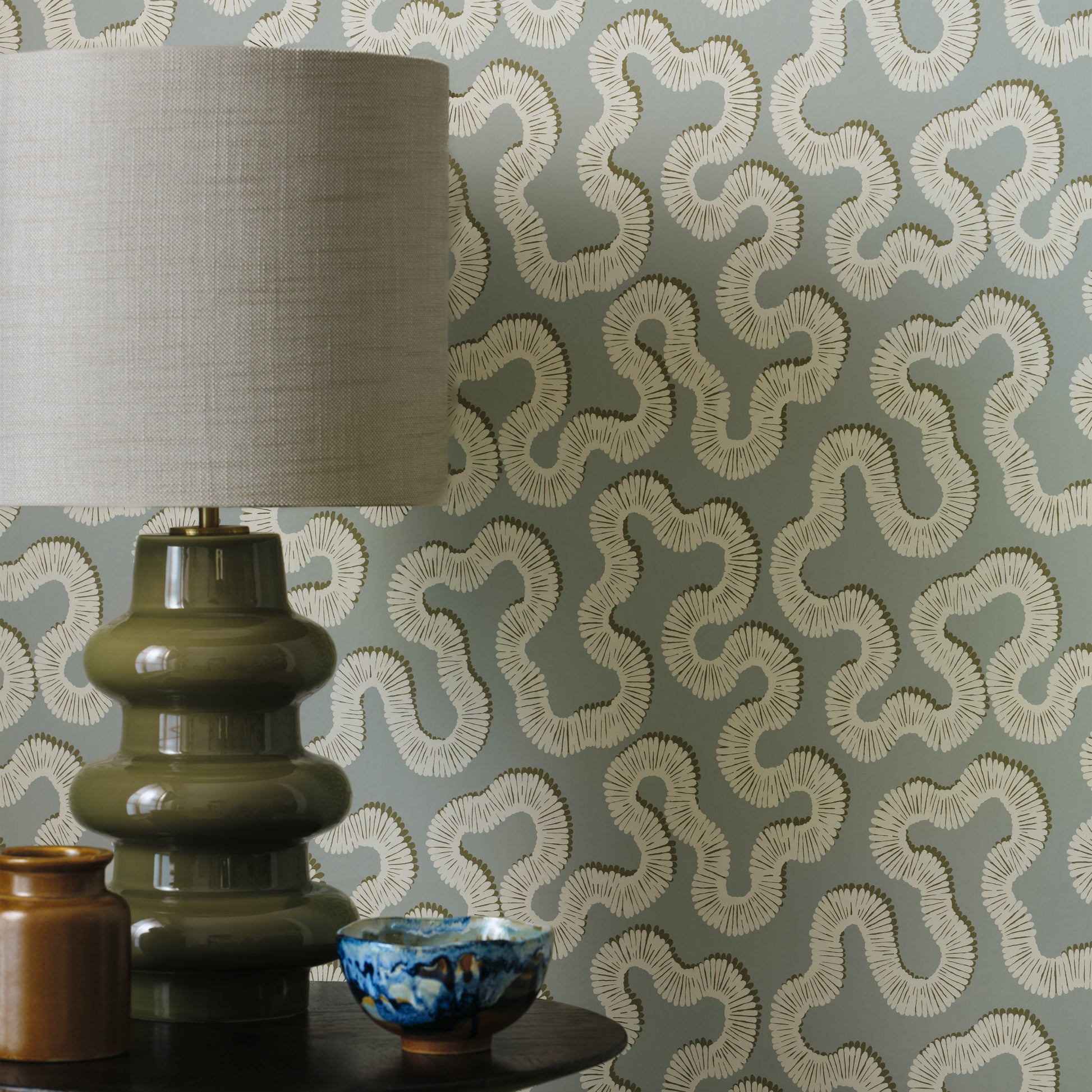 Decorative lamp and vases against a patterned wallpaper background