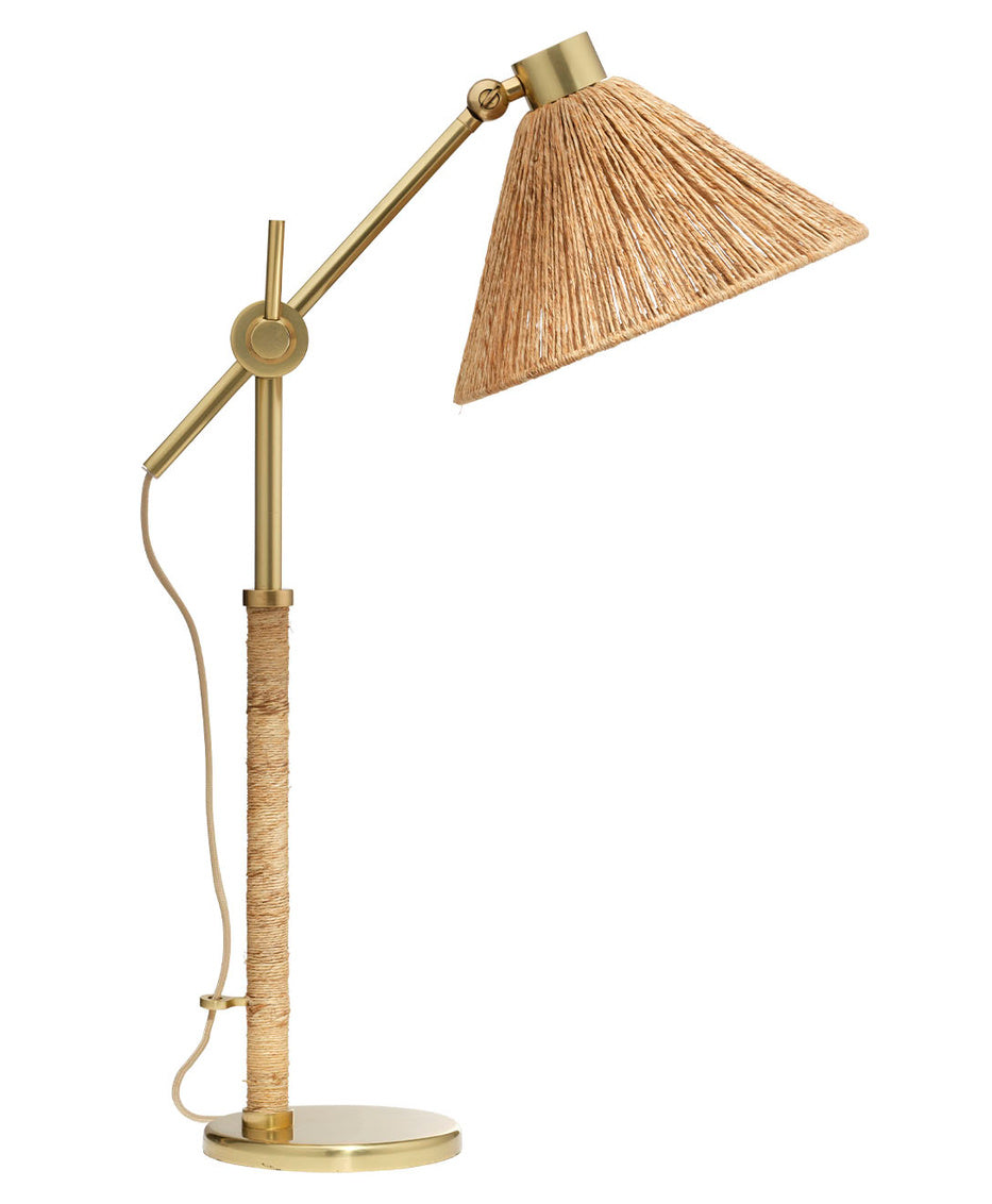 Gold table lamp with a wicker shade on a white background