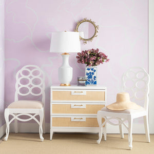 Room interior with a purple wall, white chairs, a lamp, and decorative items.