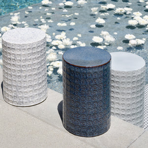 Three cylindrical stools with textured surfaces by a poolside.