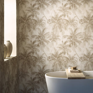 Palm tree patterned wallpaper in a warm beige and brown tone, shown on a bathroom wall with a white bathtub and a recessed shelf with ceramic vases.