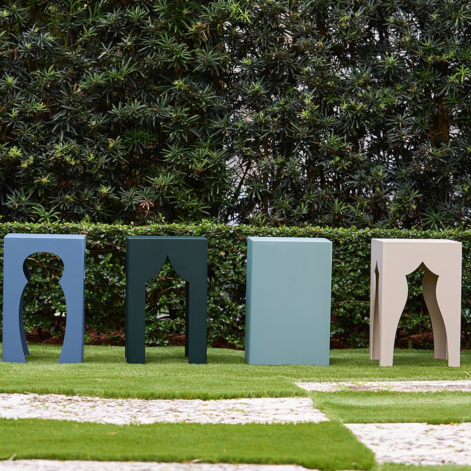 Colorful outdoor stools arranged on a grassy area with a hedge in the background